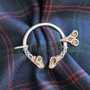 The Dunface Penannular has S curve accents and rams head ends. Shown in sterling & 14kt rose gold on Clan Hume tartan.