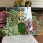 14kt yellow gold pendant with leaves and curls above a 20.71ct Green Tourmaline and accented with a Rainbow Moonstone. 
