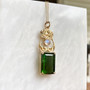14kt yellow gold pendant with leaves and curls above a 20.71ct Green Tourmaline and accented with a Rainbow Moonstone. 