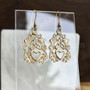 The Mìn Earrings features thistles, leaves, a trinity knot and a heart. Shown in yellow gold.