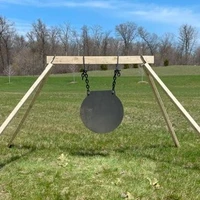 Steel gong target system positioned in rural field environment with shooter engaging at distance, demonstrating real-world long-range practice conditions.