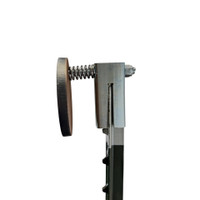 Steel round target reacting to bullet impact, swinging slightly on hanger while deflecting splatter downward for safer shooting feedback