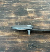 Installed steel target hanging from rubber strap on 2x4 wooden stand, swinging slightly after impact during outdoor rifle and pistol range training session.
