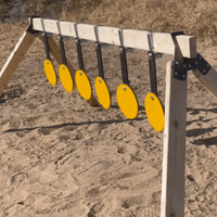 Shooter resetting steel plate rack system after impacts, showing quick-return swinging targets and efficient range maintenance workflow in outdoor setting.