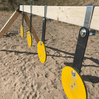 Wide-angle view of steel shooting range with multiple AR500 plate rack systems built from 2x4 frames, used for group training and practice sessions.