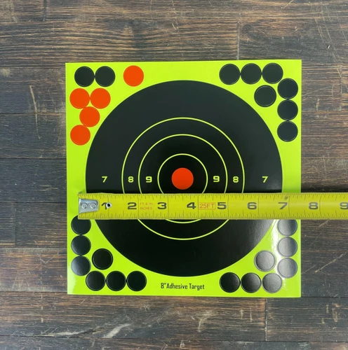 Close-up detail of adhesive splatter target surface revealing bright neon impact marks and scoring zones highlighting bullet strike locations on cardboard backing.
