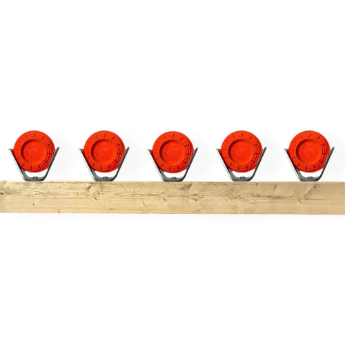 Installed clay pigeon holders securing 108mm sporting clays on wooden 2x4 beam for reactive rimfire shooting drills with visible dust impact feedback