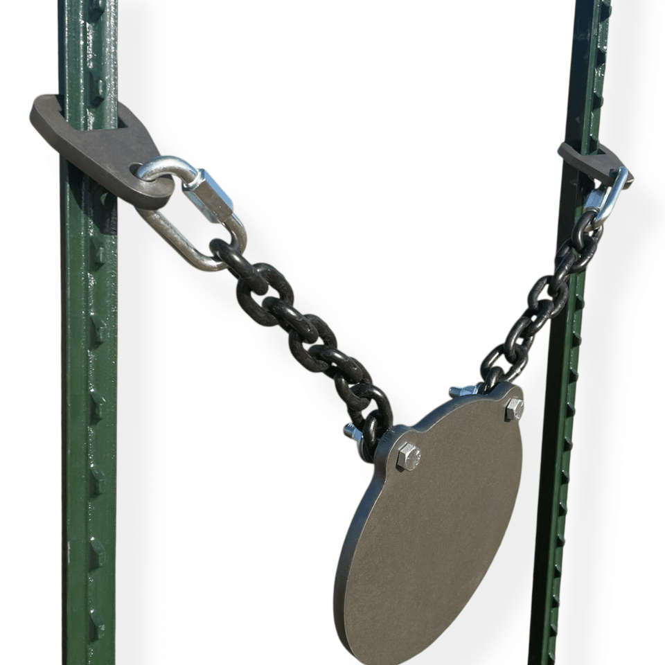 Installed AR500 steel gong target mounted between fence posts in outdoor range setting for long-distance rifle shooting practice and training sessions