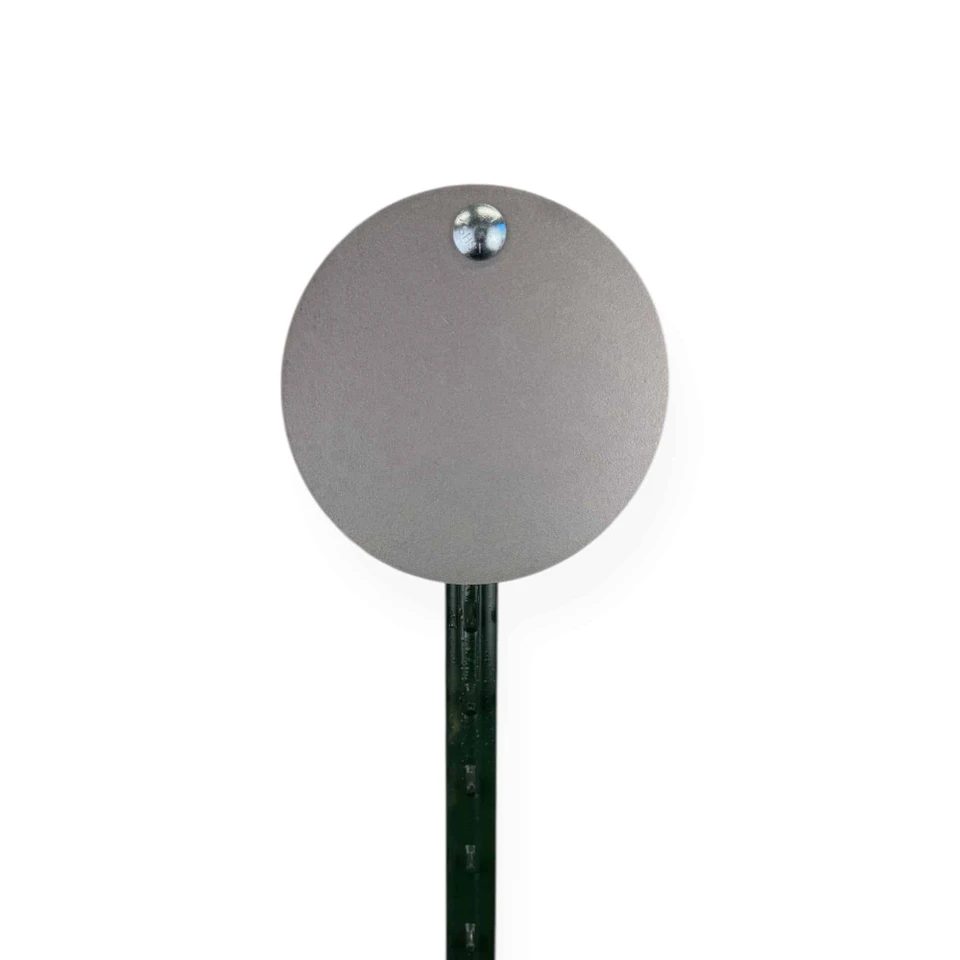 Outdoor shooting range setup with steel targets attached to T-post system, arranged for pistol accuracy and rifle transition drills in rural environment.