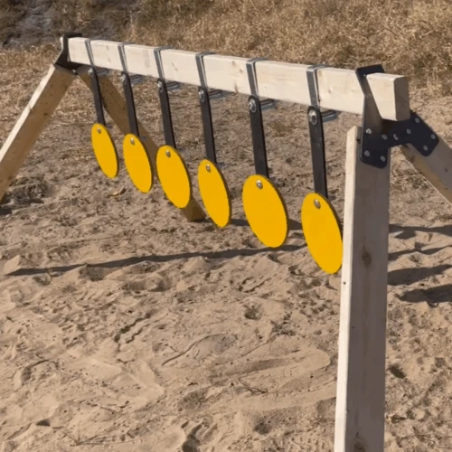 Shooter resetting steel plate rack system after impacts, showing quick-return swinging targets and efficient range maintenance workflow in outdoor setting.