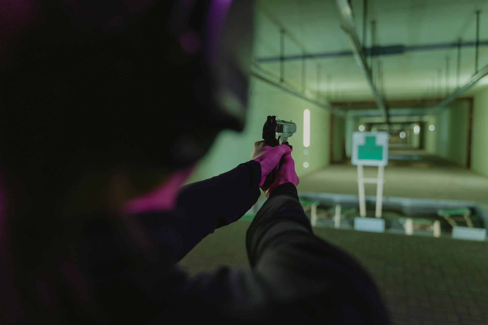 Person aiming gun at target in gun range