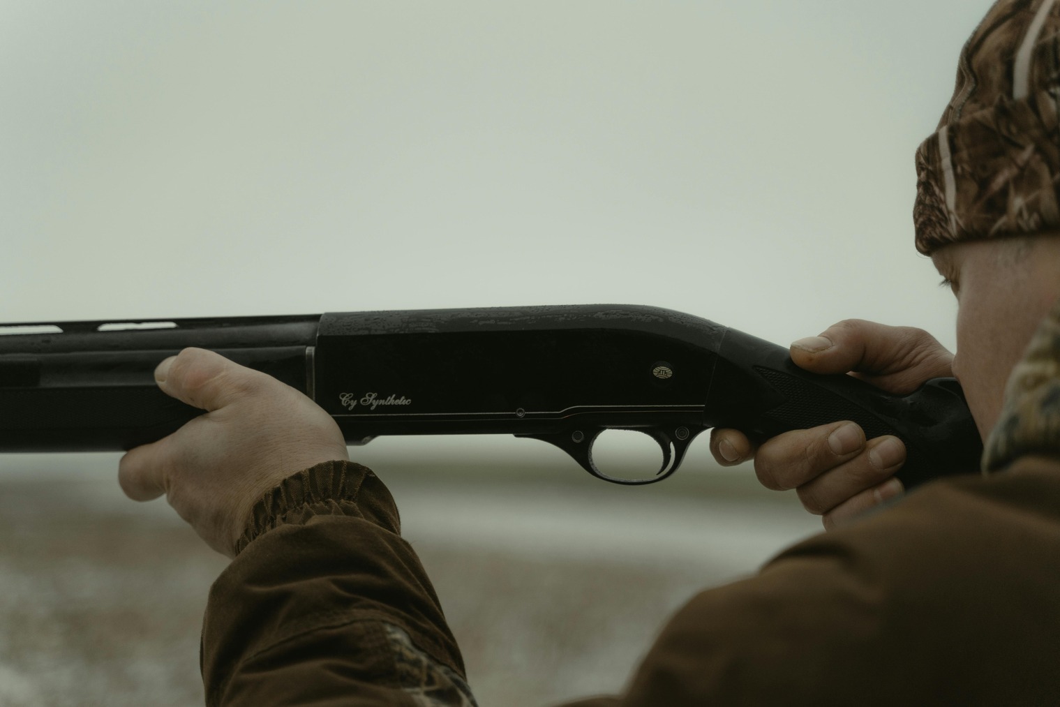 Man holds shotgun with his trigger finger away from the trigger