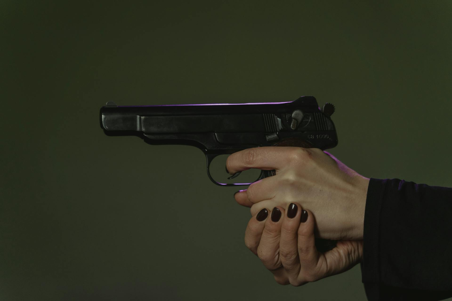 A woman’s hands aiming a pistol