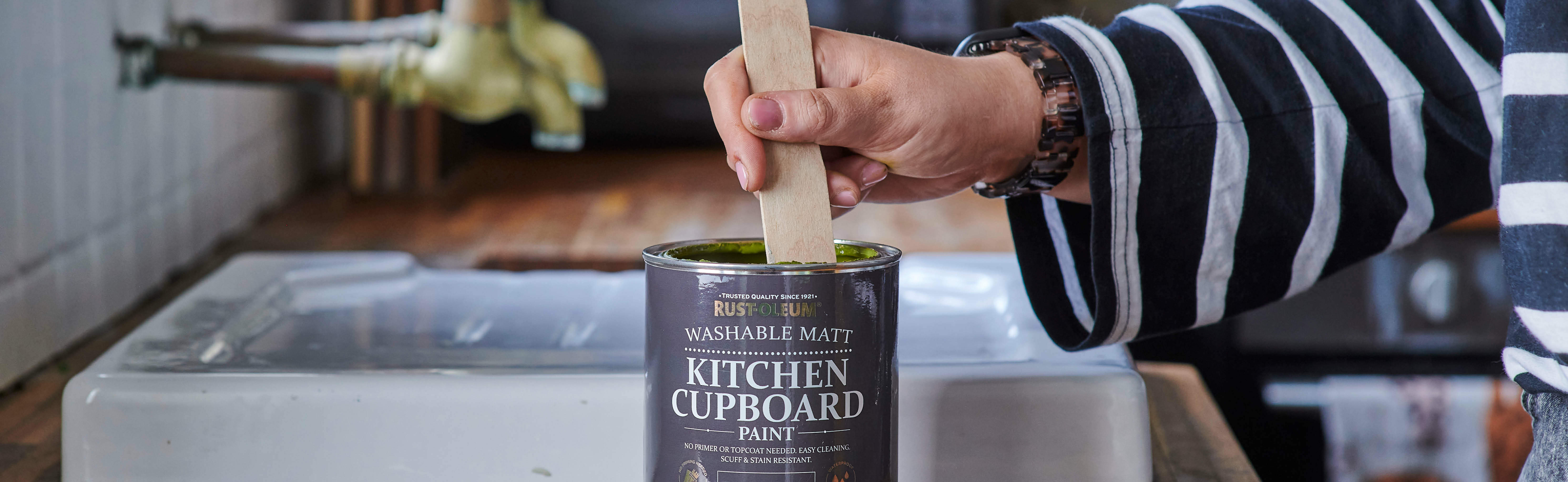 Stirring a can of Kitchen Cupboard Paint in rich green Jasper