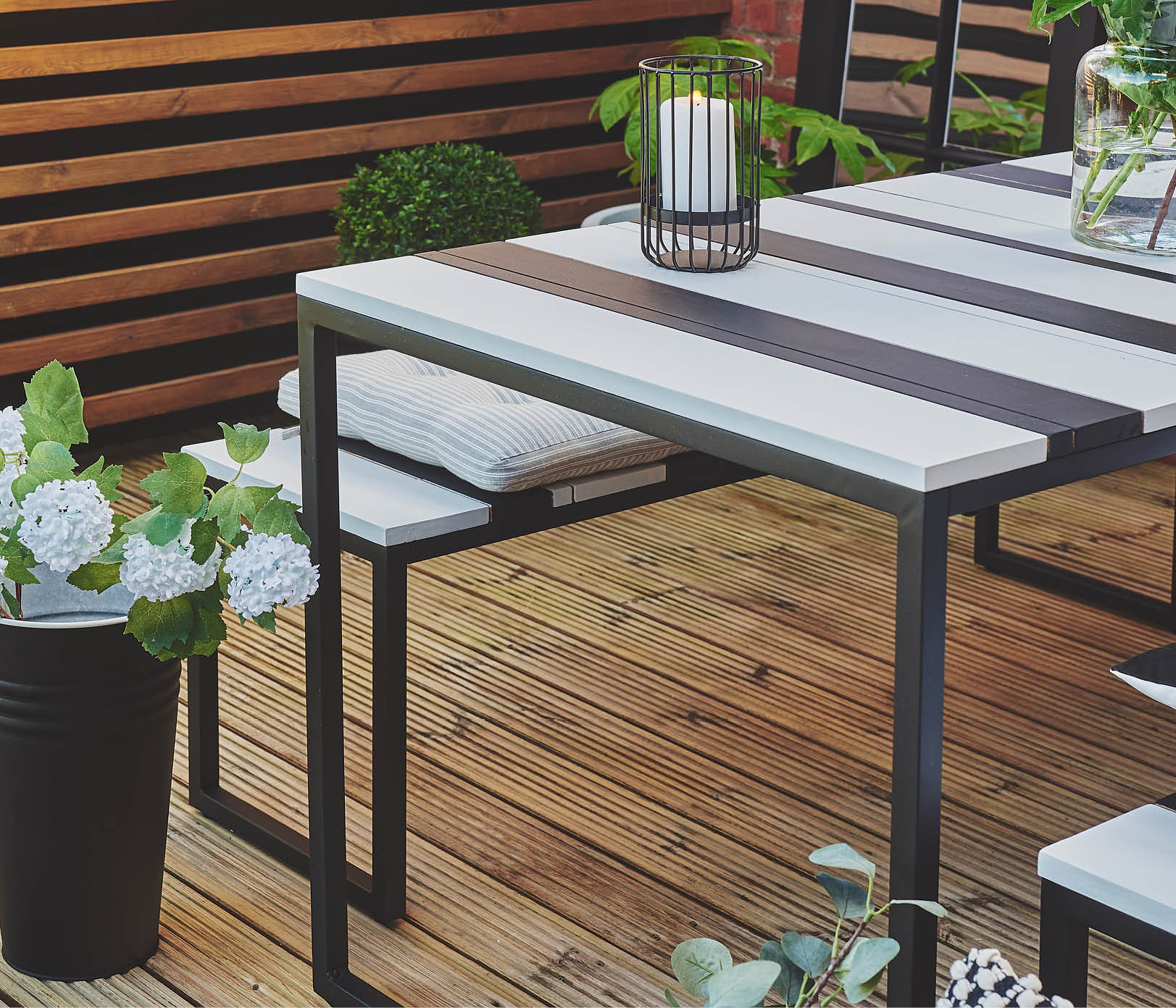 A white ornate table painted in the off-white colour Still surrounded by flowers and a black shed painted in Natural Charcoal