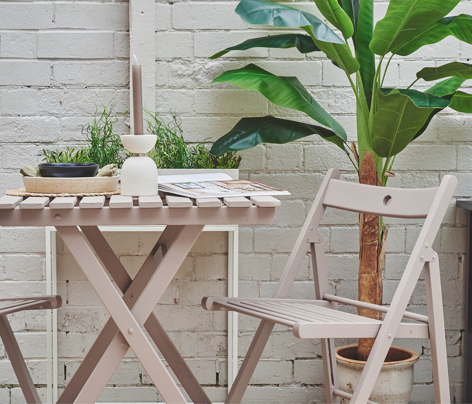 A beige brick wall painted in Half Light and a taupe patio table and chair set painted in Cocoa