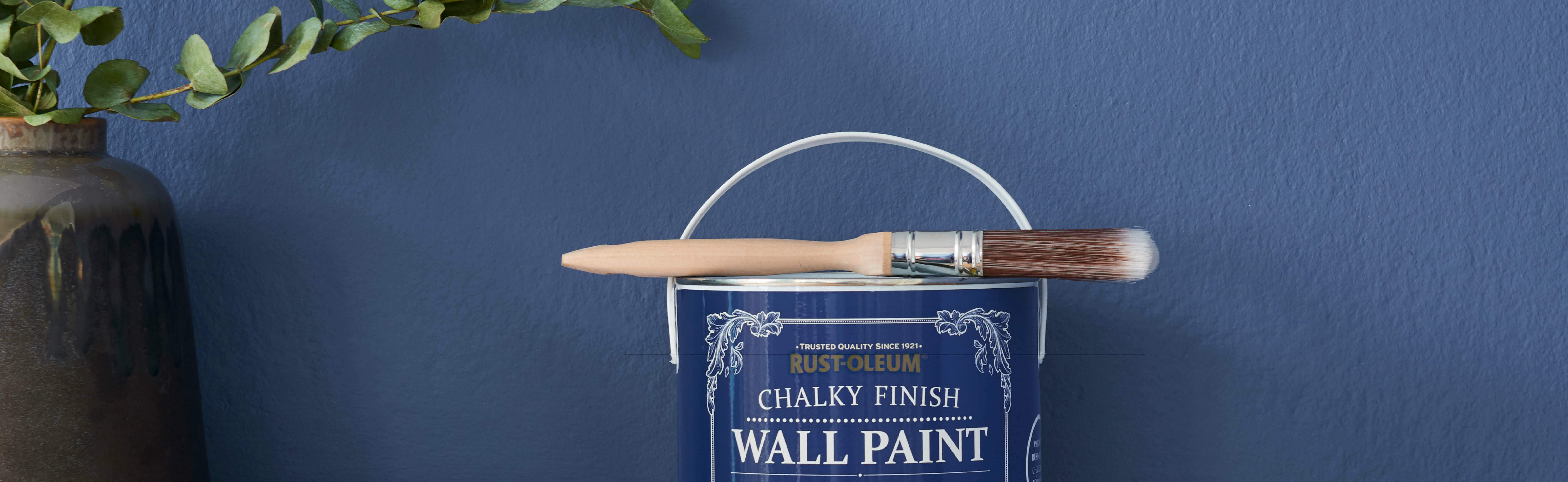 A deep blue wall painted in Blue River behind a can of Chalky Wall Paint