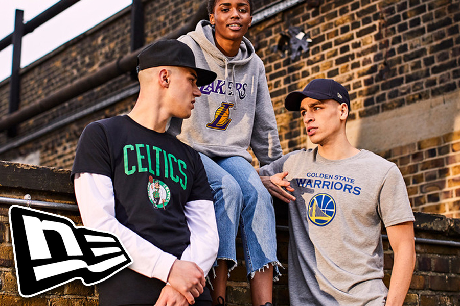 A group of nicely dressed people wearing New Era NBA clothing conversating whilst leaning on a brick wall