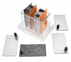 Electrochemical reaction kit shown on a clean white background with a clear plastic battery box, copper electrode plates, and interchangeable metal electrodes with black binding posts for wet cell battery experiments.