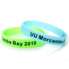 A set of glow-in-the-dark silicon wristbands in green and blue, featuring a logo and text.