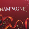 A close-up of a red background featuring festive decorations and the word "Champagne" in elegant lettering.