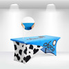 A blue and white stretch table cloth with a cow print design, featuring a branding logo on the top.