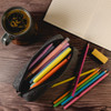 A grey felt utility case filled with colourful pens and pencils, alongside a notepad and a coffee cup.