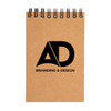 A spiral-bound pocket notebook with a kraft cover featuring the logo "AD" along with the text "BRANDING & DESIGN".