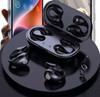 Black Clipz TWS earbuds displayed in a charging case, with a smartphone partially visible in the background.