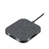A square wireless charger in grey fabric with a black base, featuring a charging cable attached.