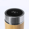 A drink bottle with a bamboo exterior and stainless steel top, featuring a digital temperature display.