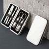 A sleek white Zoel manicure set containing silver nail clippers, scissors, tweezers, and a file in a compact case.