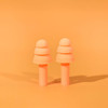 A pair of peach silicone earplugs on an orange background, designed for noise reduction, featuring a simple and smooth shape.