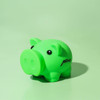 A green pig-shaped money box with black eyes and a logo on its side, set against a mint green background.