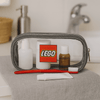 A grey clear travel case containing a toothbrush, toiletry bottles, and a tube, with a logo visible on the front.