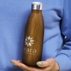 A drink bottle with a brown wood-like finish, featuring a logo and a stainless steel lid, held in a person's hand.