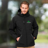 A man wearing a black softshell jacket featuring a logo, with a hood and zippered pockets.