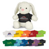 A white plush rabbit wearing a black t-shirt, surrounded by various colourful toy t-shirts in multiple shades.