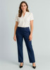 A woman stands wearing navy relaxed pants paired with a white blouse and black shoes. The pants have a subtle logo.