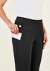 A pair of black women's 3/4 length stretch pants with a pocket, shown being held by a model.