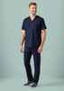 A man wearing a navy scrub top with a V-neck and two front pockets, paired with navy scrub pants.