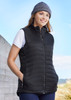 A black women's expedition vest with zip front and side pockets, worn by a woman in a knit beanie against an outdoor backdrop.