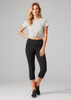 A model wears women's black 3/4 leggings paired with a grey knotted t-shirt. The leggings have a logo on the waistband.