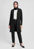 A longline cardigan in black, paired with a white blouse and black trousers, worn by a woman in a hijab.