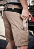 Men's beige work shorts with multiple pockets, featuring a tool in one pocket and a logo on the waistband.