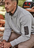 A man wearing a grey unisex 1/4 zip brushed fleece pullover with a logo on the sleeve, seated outdoors.