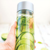 A drink bottle with a silver lid, featuring clear body filled with water, cucumber slices, and mint leaves.