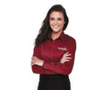 A woman poses confidently in a burgundy long sleeve button-up shirt, featuring a logo on the chest.