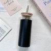 A drink bottle with a black base and clear glass top, featuring a wooden lid and a metal straw.