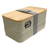 A two-tier wheat straw lunch box in a light beige colour with a bamboo lid and grey strap. Features a logo.